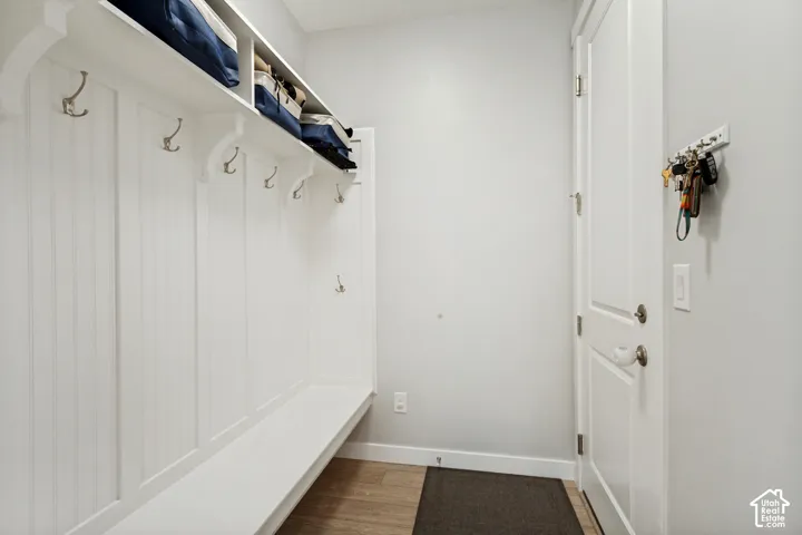 Built-in white storage bench with beadboard backing, overhead shelf, and multiple coat hooks