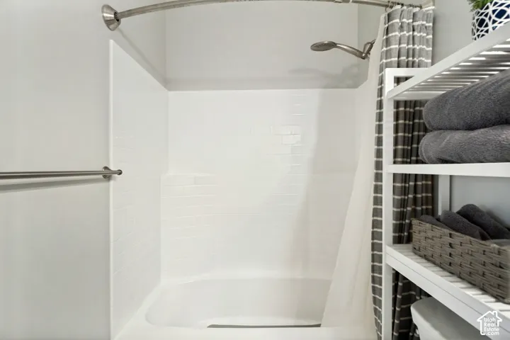 Bathtub with an integrated shower, white subway tile-inspired surround, and a curved shower rod
