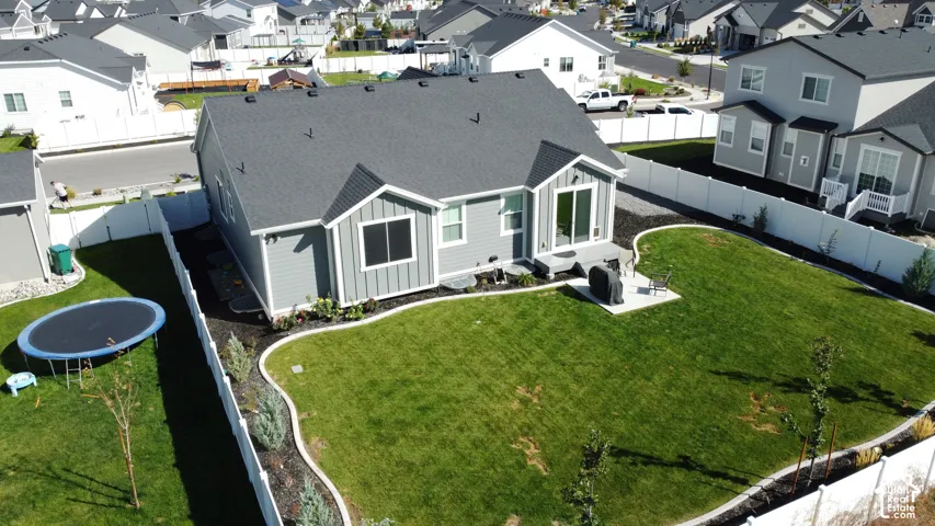 Expansive backyard with manicured lawn, established landscaping, and a concrete patio