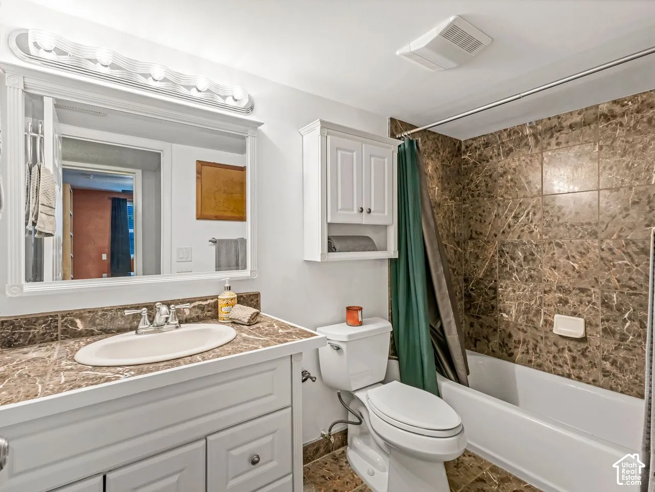 Bathroom featuring a white vanity with an undermount sink, a stone-finish countertop, and a vanity mirror with an overhead light fixture
