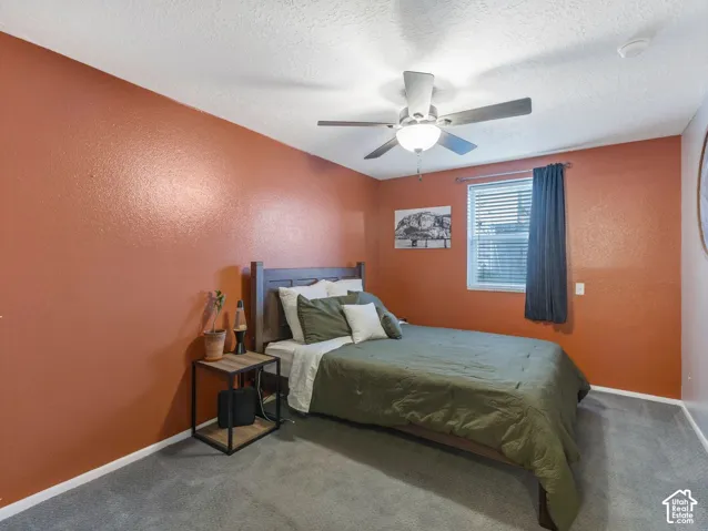 Neutral-toned carpeting, ceiling fan with integrated lighting, window with blinds, and painted walls