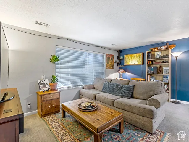 Recessed lighting, window with blinds, blue accent wall, built-in shelving, and carpeting
