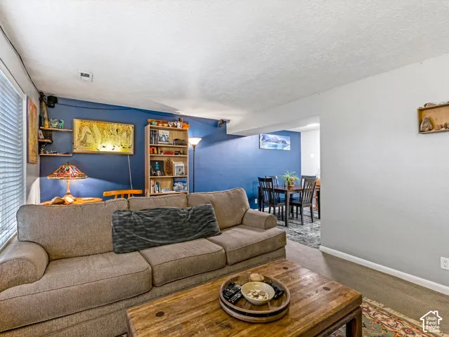 Finished basement recreation area featuring deep blue accent walls, built-in shelving with display lighting, wood-finish flooring, and a wood coffee table