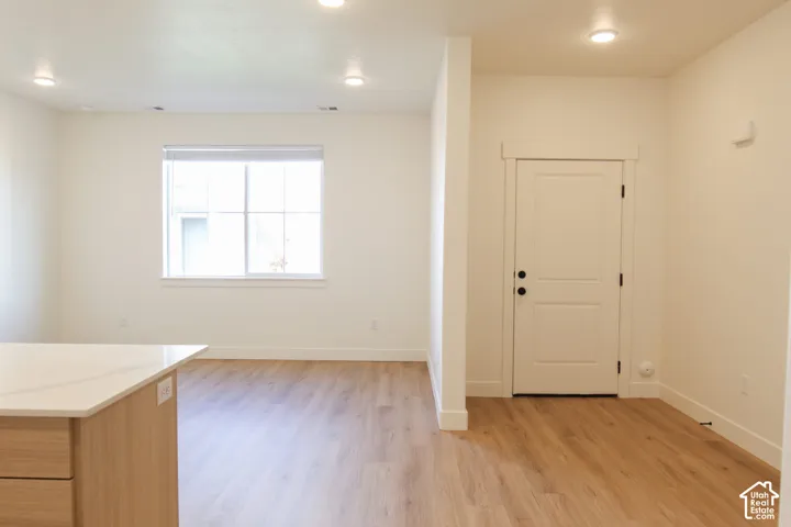 Open-concept living space featuring wood-finish flooring, recessed lighting, and a window with white trim