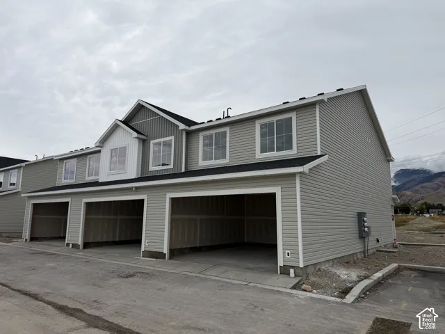 Contemporary multi-level exterior with light-colored siding, multiple windows, and a dark shingle roof