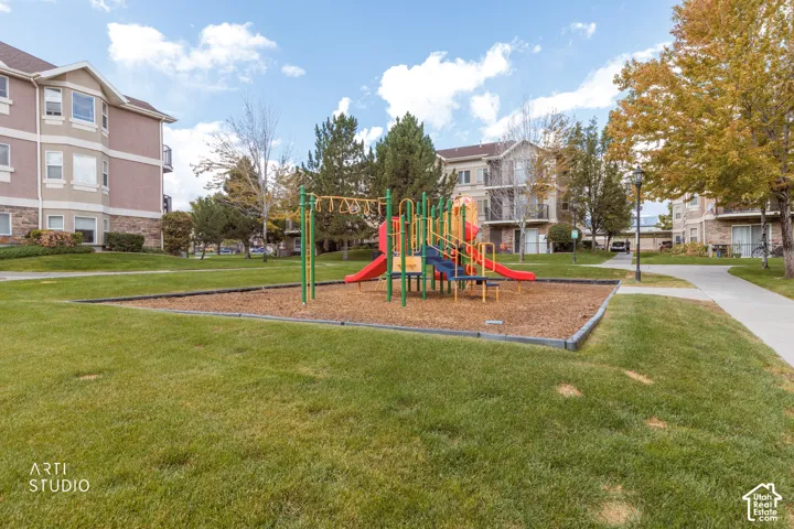 Community playground with colorful equipment, surrounded by landscaped green space and mature trees
