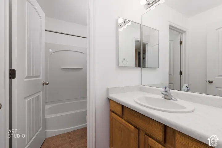 Vanity with an integrated sink and chrome faucet, wood-finish cabinetry, and a full wall mirror