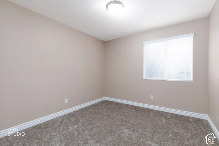 Recessed ceiling light fixture, neutral wall paint, white trim, textured carpeting, and window with blinds