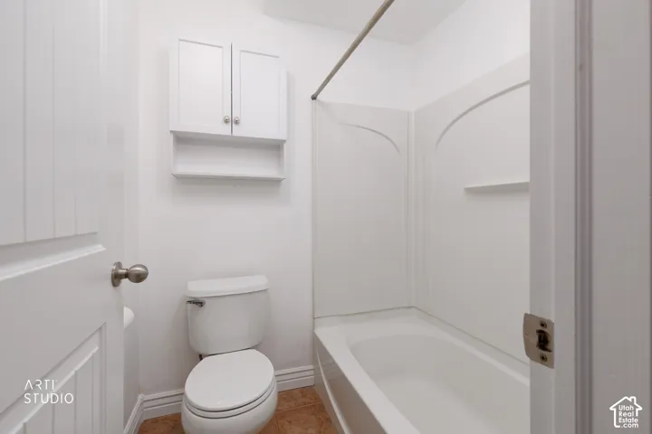 White wall-mounted cabinet with open shelving, flush-mount toilet, and a shower/tub combination with integrated shelving