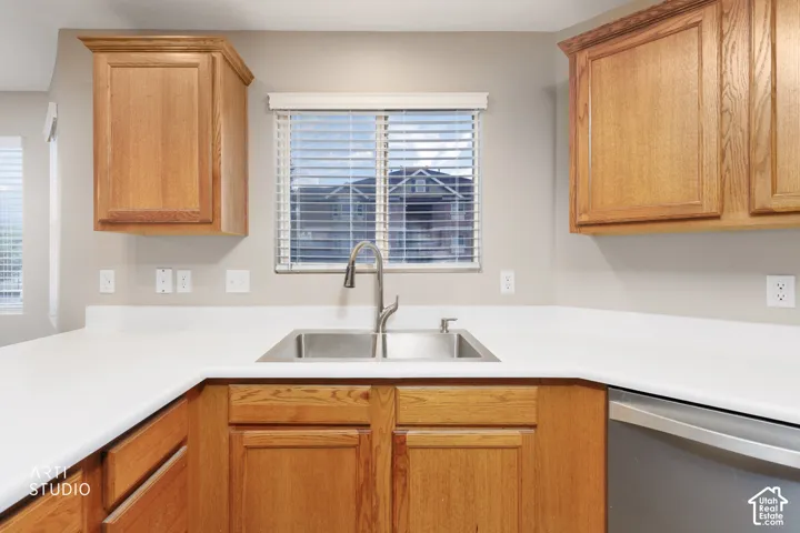 Kitchen featuring wood-finish cabinetry, light-toned countertops, and a double basin sink with a gooseneck faucet
