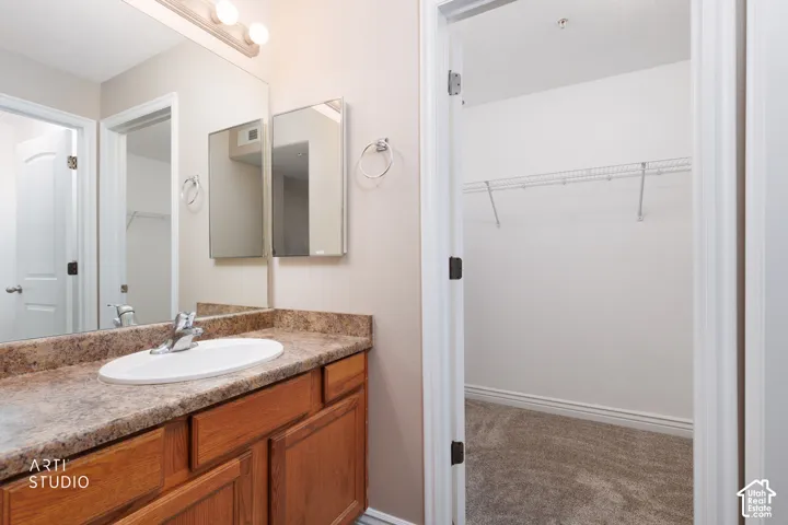 Bathroom vanity featuring a single basin sink, chrome faucet, and wood-finish cabinetry