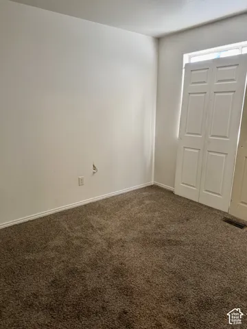 Wall-to-wall carpeting in a neutral tone and a single window providing natural light