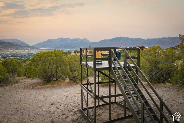 Two-story elevated deck with a durable gray finish and integrated staircase, surrounded by natural landscaping and distant mountains