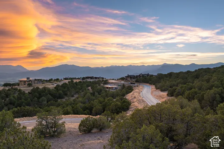 Winding paved road, surrounded by extensive natural landscaping and distant mountain ranges