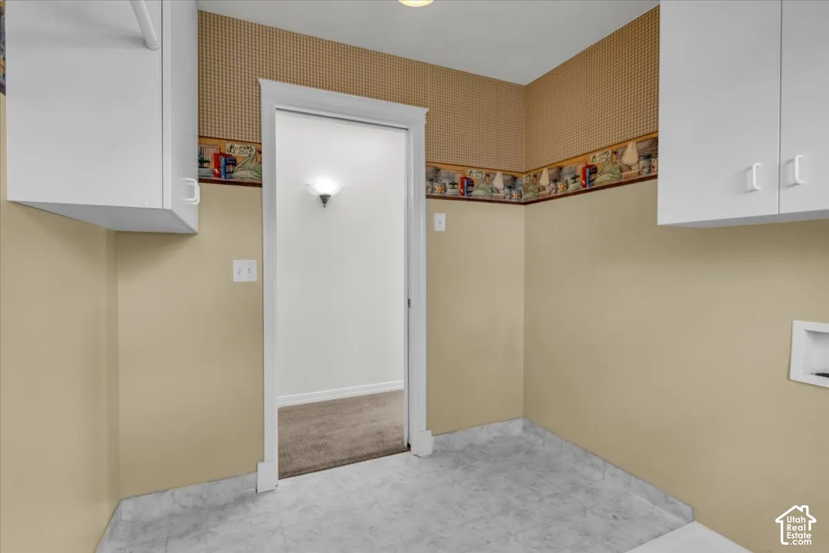 White upper cabinetry, light-toned wall paint, patterned wallpaper border, and grey flooring