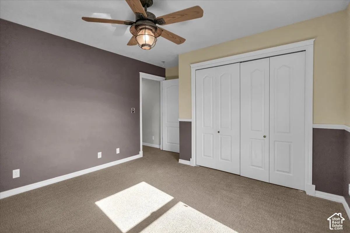 North West bedroom with Textured carpeting, two-tone wall paint, white trim, bi-fold closet doors, and a ceiling fan with integrated lighting
