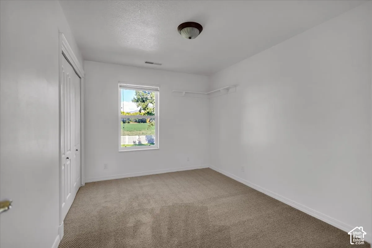 East Bedroom with Neutral wall colors, neutral carpet flooring, a window offering natural light, and a built-in closet with bi-fold doors