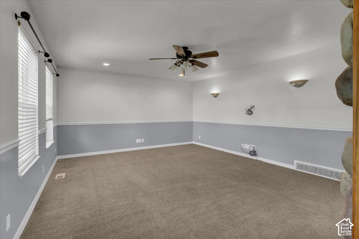 Carpeted room with white and gray walls, recessed lighting, and wall sconces