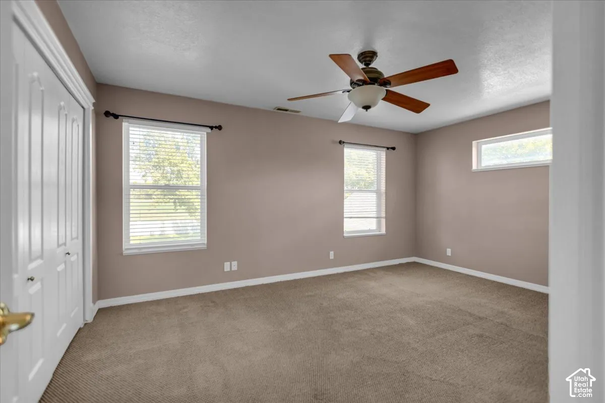 Primary Bedroom featuring a ceiling fan, dual windows with blinds, and white trim