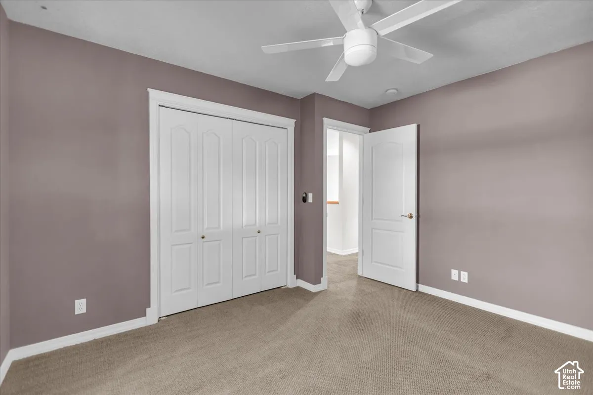 North East Bedroom with Ceiling fan, wall-to-wall carpeting, bi-fold closet doors, white trim, and a paneled door