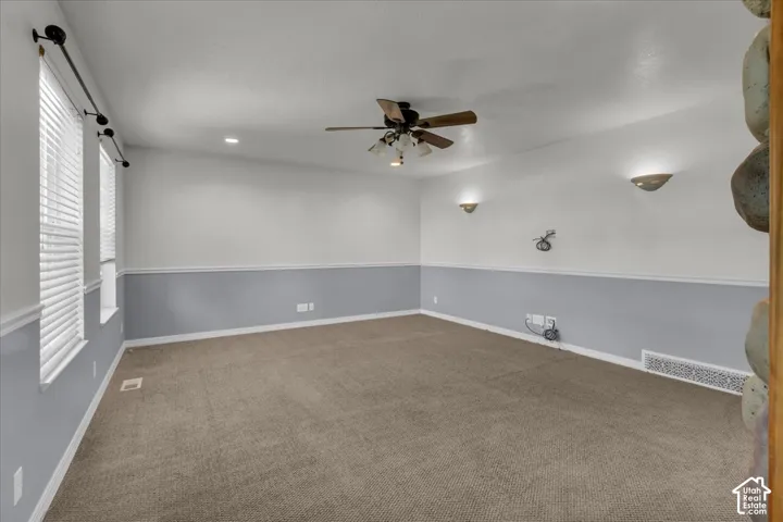 Carpeted room with white and gray walls, recessed lighting, and wall sconces