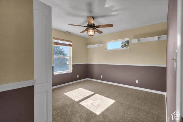 North West bedroom with featuring a ceiling fan with integrated lighting, two windows, and built-in shelving