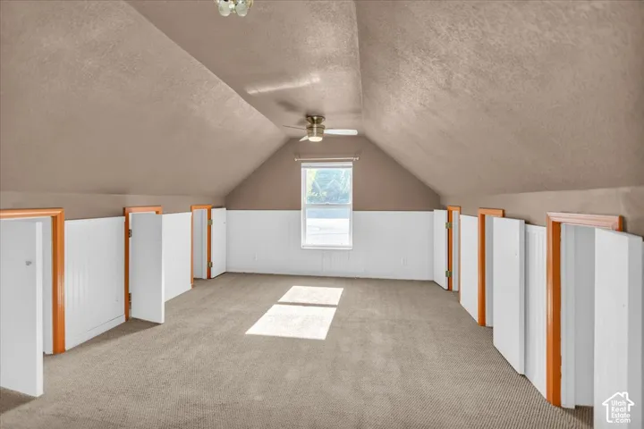 Carpeted space featuring a window, built-in storage doors, and a ceiling fan
