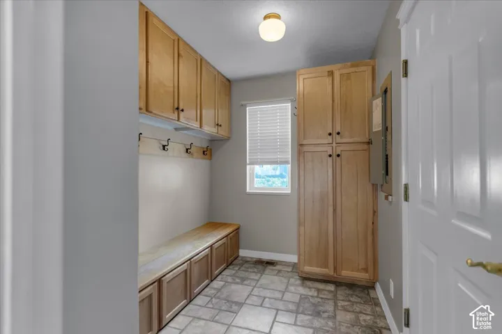 Wood-finish cabinetry, built-in storage bench, and ceramic tile flooring
