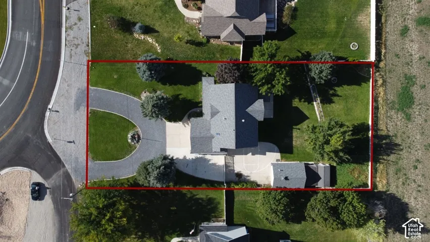 Expansive lot with a circular driveway, mature trees, and an additional detached structure