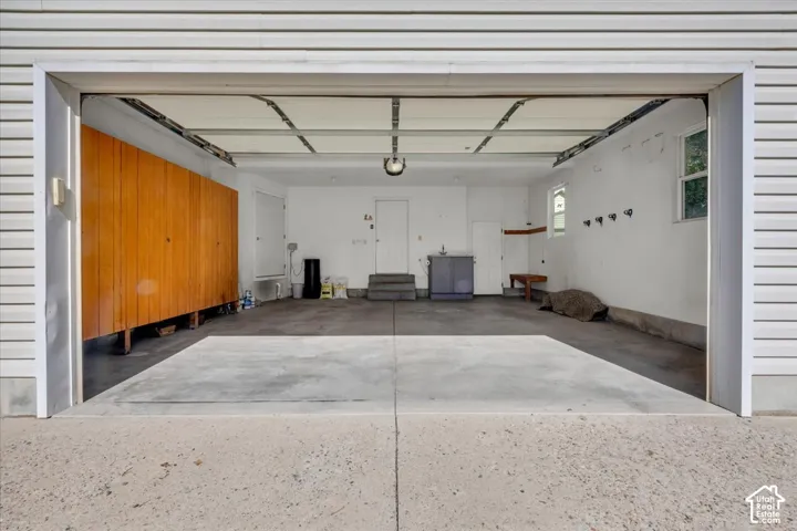 Spacious garage with concrete flooring, integrated wood-finish cabinetry, and built-in wall hooks