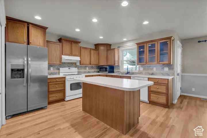 Kitchen featuring wood-finish flooring, recessed lighting, wood cabinetry, a center island, and a mosaic tile backsplash