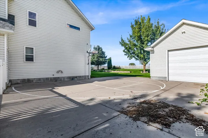 Paved concrete surface with painted court lines and an attached basketball hoop