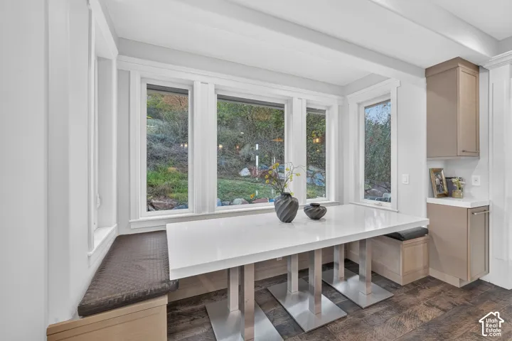 Built-in bench seating with cushion, white countertop, multiple windows, built-in cabinetry, and wood-finish flooring