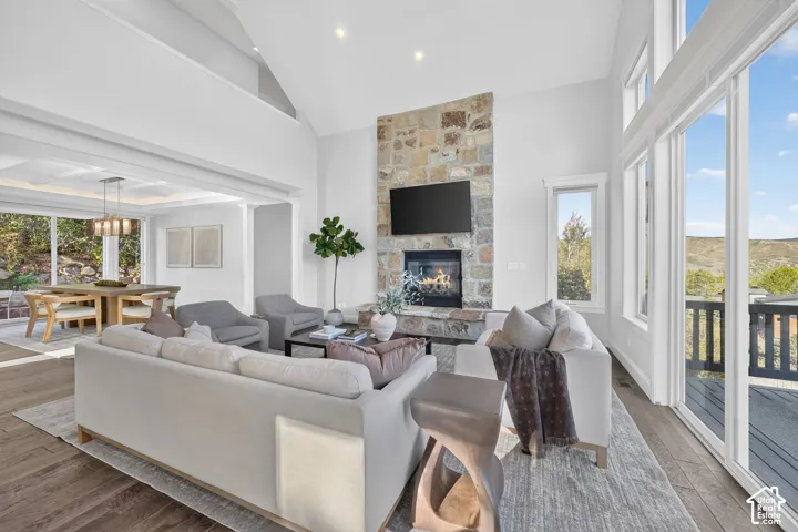 Living room featuring a vaulted ceiling, stone-clad fireplace with a built-in television, and wood-finish flooring
