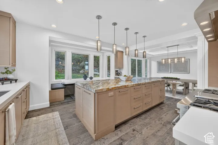 Spacious kitchen featuring a large central island with a stone countertop, wood-finish cabinetry, and industrial-style pendant lighting