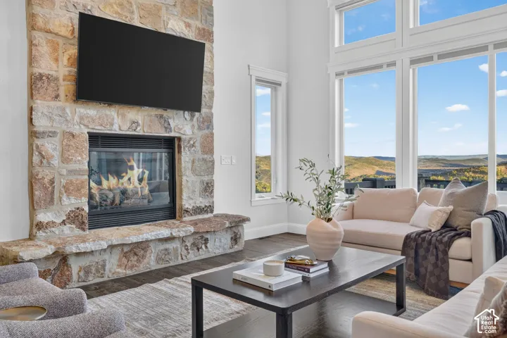 Stone-clad fireplace with a hearth, expansive multi-pane windows, and wood-finish flooring