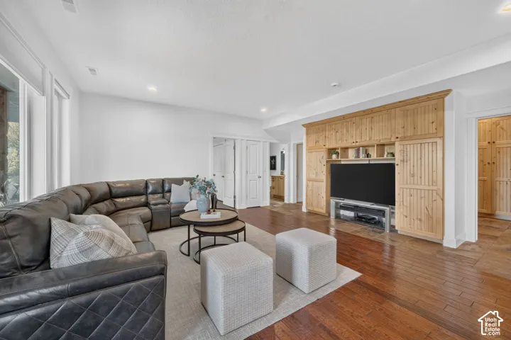 Hardwood flooring, recessed lighting, and a built-in entertainment center with natural wood cabinetry