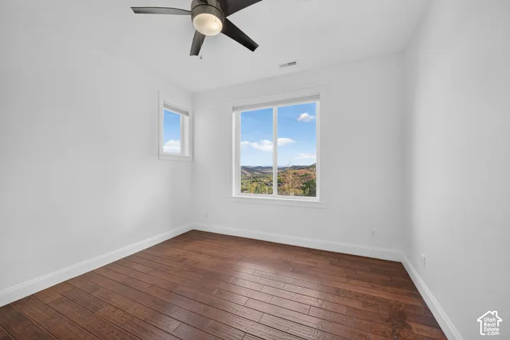 Wood-finish flooring, white walls, and a ceiling fan with integrated lighting