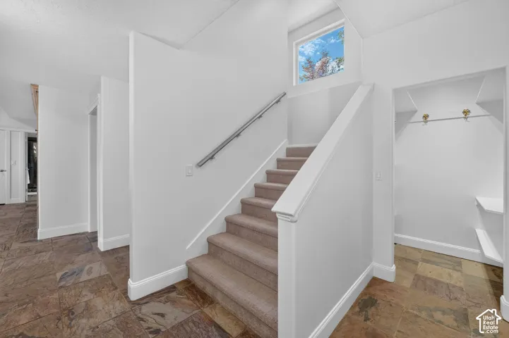 Staircase featuring carpeted treads and a metal handrail