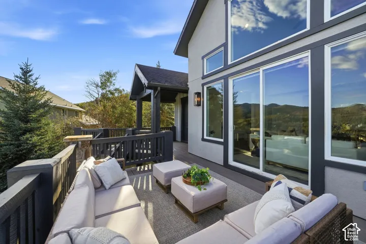 Expansive outdoor deck with dark wood railing and a covered porch area