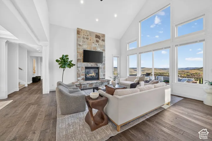 Vaulted ceilings, a stone fireplace, wood-finish flooring, and expansive windows showcasing a scenic landscape