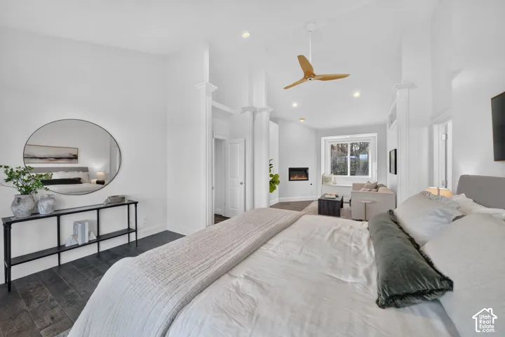 Dark wood-finish flooring, vaulted ceiling with recessed lighting, modern ceiling fan, built-in fireplace, and a large window