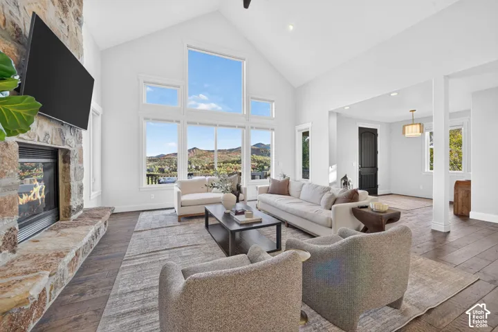 Vaulted ceiling, stone-clad fireplace, large picture windows, wood-finish flooring, and recessed lighting