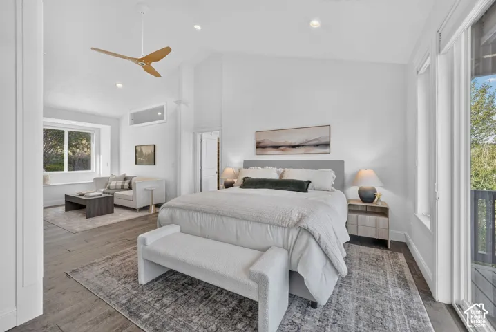 Vaulted ceiling with a wood-finish ceiling fan, recessed lighting, wood-finish flooring, and a large sliding glass door opening to an outdoor deck