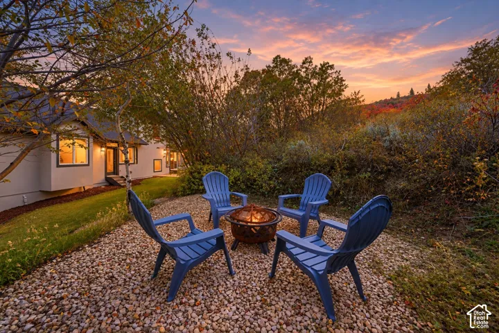Gravel outdoor area with a fire pit, surrounded by natural landscaping and mature trees
