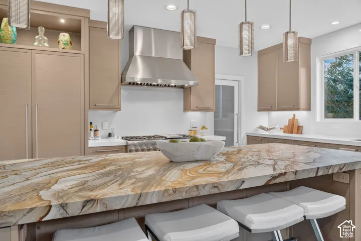 Expansive kitchen island with a unique natural stone countertop, professional-grade stainless steel range with hood, integrated refrigerator, and warm wood-finish cabinetry