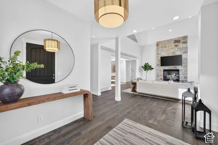 Hardwood-style flooring throughout, stone-clad fireplace with mantel, recessed lighting, and a modern overhead light fixture
