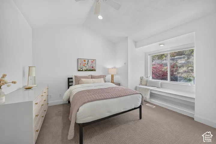 Vaulted ceiling with a ceiling fan, recessed lighting, built-in window bench, and an expansive window