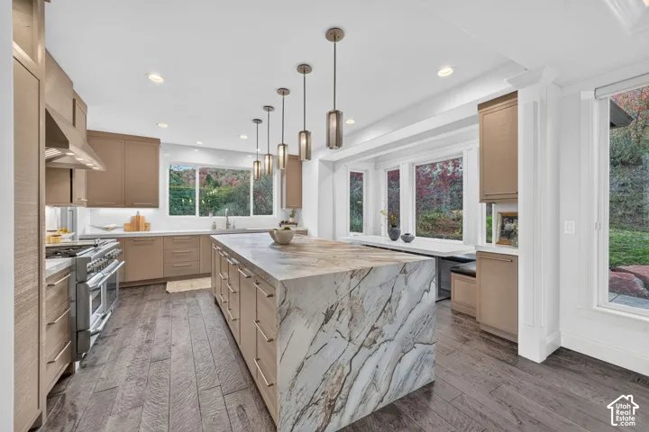 Spacious kitchen featuring a large waterfall island, wood-finish flooring, recessed lighting, and expansive windows