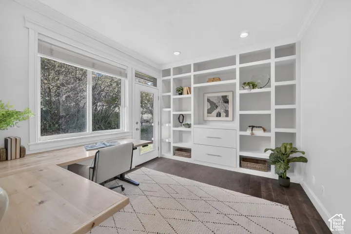 Built-in shelving with integrated drawers, recessed lighting, wood-finish flooring, and a glass-paneled exterior door